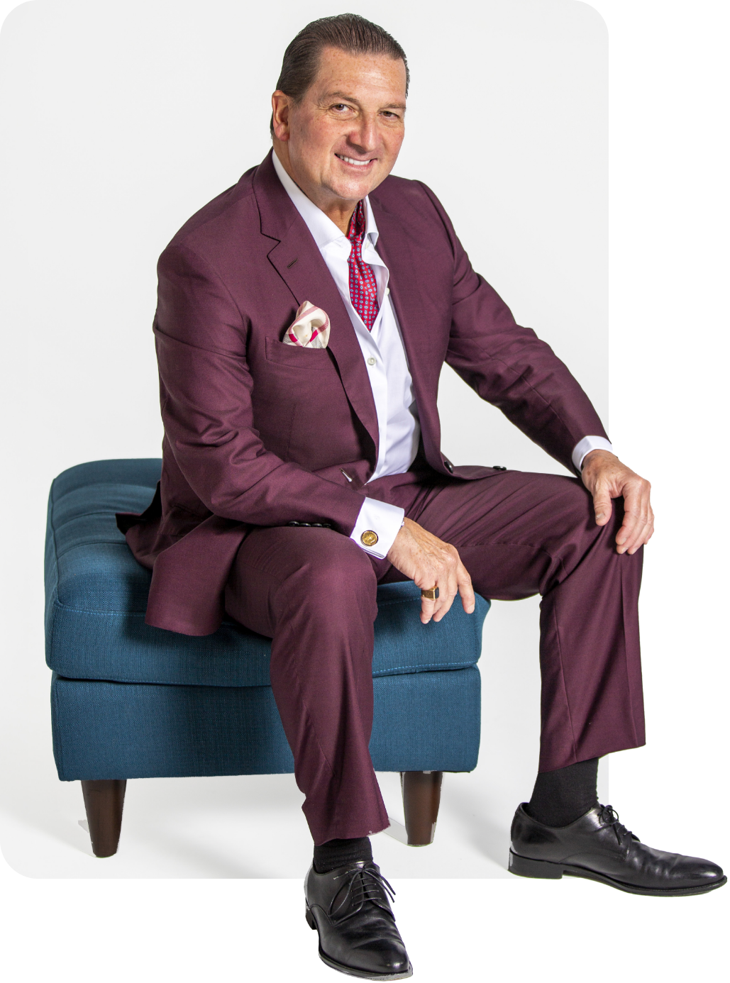 Dr. Newall smiling and sitting on a blue ottoman